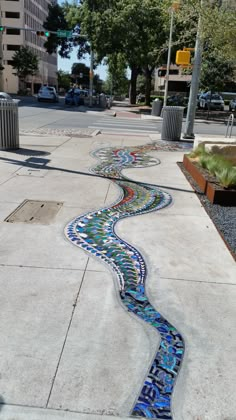 a sidewalk that has been decorated with colorful tiles on the side and water running through it