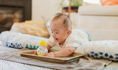 a baby is playing with a toy in a tray on the floor next to a couch