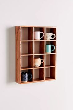 a wooden shelf filled with cups and mugs on top of white wall mounted shelves