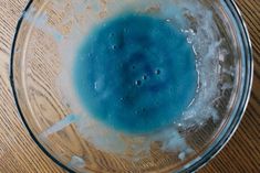 a glass bowl filled with blue liquid on top of a wooden table