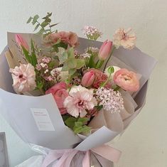 a bouquet of flowers is wrapped in gray paper and tied with pink ribbon around it