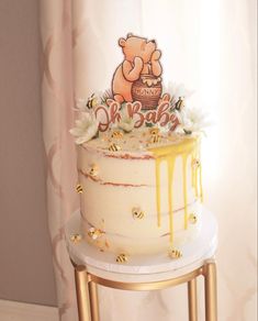 a birthday cake with honey drips and a winnie the pooh decoration on top