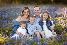 a family sitting in a field of bluebonallions posing for a photo with their two children