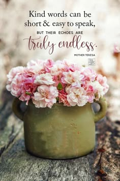 a green vase filled with pink flowers sitting on top of a wooden table next to a quote