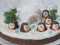 a cake with frosting and penguins on it, surrounded by other decorations in the shape of an igloose