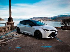 a white car parked in front of a body of water