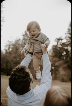 a man holding a baby up in the air