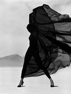 a black and white photo of a woman in high heels with her dress blowing in the wind