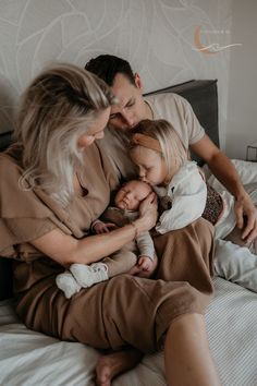 a man, woman and child are sitting on a bed with their hands around each other