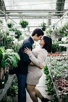 a man and woman kissing in a greenhouse