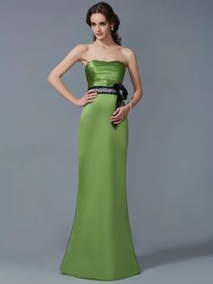 a woman in a strapless green dress posing for the camera with her hands on her hips