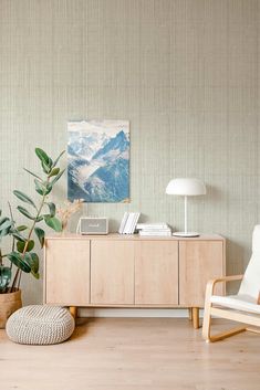 a living room with wooden furniture and green wallpaper on the walls, along with a plant