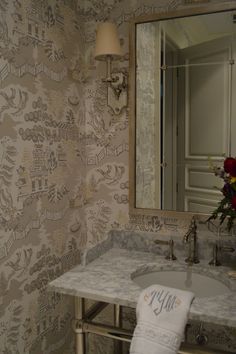 a white sink sitting under a bathroom mirror next to a wall mounted faucet