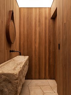 a stone bench sitting in front of a wooden wall with a skylight above it