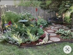 a garden with lots of flowers and plants in the center, surrounded by gravel stepping stones