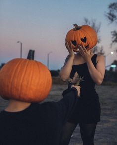 two people with pumpkins on their heads, one holding the other's face