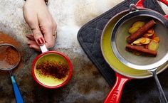 two people are cooking food in pans on the stove top, and one person is holding a spoon