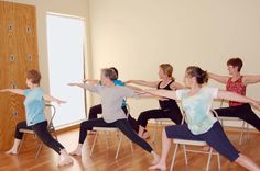 a group of people doing yoga poses in a room with wooden floors and walls,