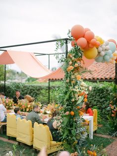 an outdoor dining area with yellow chairs and balloons