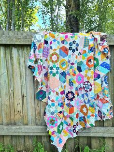 a colorful quilt hanging on a wooden fence