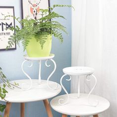 two small white tables with plants on them