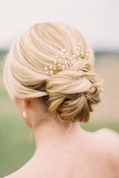 a woman with blonde hair wearing a bridal hairstyle and pearls in her hair