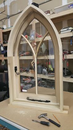 a wooden window sitting on top of a table in a room filled with shelves and tools