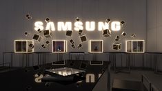 the samsung logo is lit up in front of an office desk with multiple frames on it