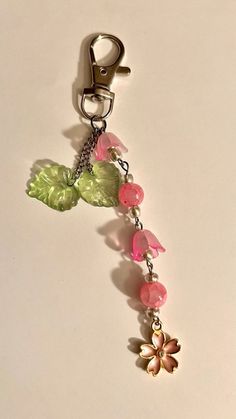 a keychain with flowers and leaves attached to it's back end on a white surface