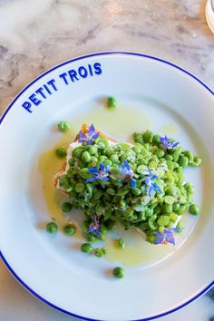 a white plate topped with green peas covered in sauce and blue writing on the side