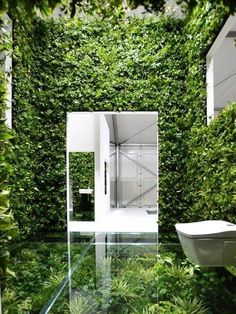 the bathroom is surrounded by greenery and has a white toilet in it's center