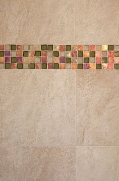 a bathroom with a tiled wall and floor next to a shower head mounted faucet