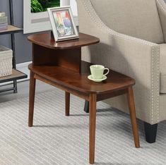 a small wooden table with a coffee cup on it next to a couch and chair