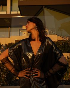 Indulge in the art of self-expression in this decadent metallic caftan. This exquisite garment is more than just a piece of clothing; it's a celebration of fabric in all its glory. Crafted with generous amounts of a slinky black jersey coated in a gorgeous mercurial foil and lots of love, this piece offers an airy fit designed to drape beautifully on all body types. Whether worn over a swimsuit for a day at the beach or layered and adorned with your favorite accessories for a glamorous evening a Gold V-neck Kaftan For Party, Gold Kaftan For Party And Festive Occasions, Elegant Dresses With Kimono Sleeves For Festivals, Festive Dress With Kimono Sleeves, Glamorous Festive Evening Kaftan, Festive Silver Dress For Celebration, Festive Silver Celebration Dress, Evening Kaftan With Kimono Sleeves, Brand Magazine