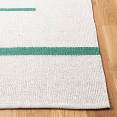 a white rug with green stripes on top of wooden flooring next to a wood floor