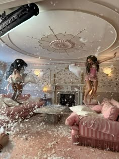 two girls jumping in the air with snow falling all over them and furniture scattered around