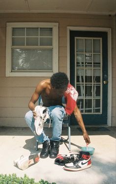 a shirtless man sitting in a chair with his skateboard on the front porch