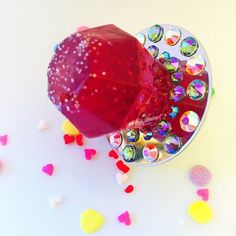 a red apple sitting on top of a mirror covered in confetti