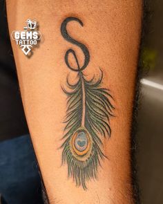 a man's arm with a tattoo on it that has a musical note and a peacock feather