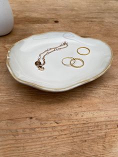 a white plate with two rings on it sitting on a table next to a vase