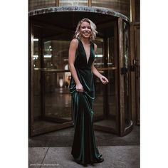 a woman standing in front of a glass door wearing a green dress and smiling at the camera