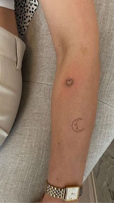 a woman's arm with a small sun and moon tattoo on it