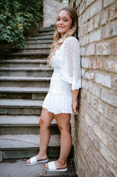 a beautiful young woman leaning against a brick wall