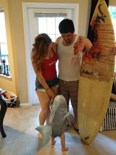 a man standing next to a woman holding a surfboard