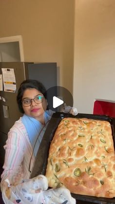 a woman holding up a large loaf of bread