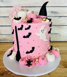 a pink halloween cake with black and white decorations on the top is decorated with gold accents