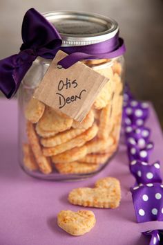 a jar filled with cheesy crackers on top of a purple table cloth