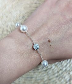 a woman's arm wearing a bracelet with pearls and a crystal ball on it