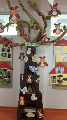 a tree made out of cardboard with pictures on the branches and paper owls hanging from it