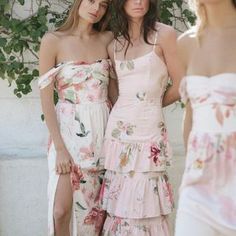 three women standing next to each other in dresses